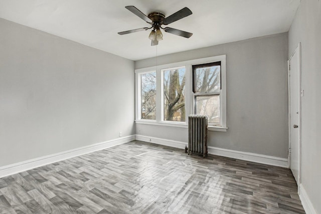 empty room with radiator, hardwood / wood-style floors, and ceiling fan