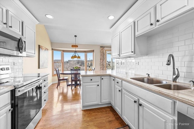 kitchen featuring appliances with stainless steel finishes, pendant lighting, white cabinetry, sink, and light wood-type flooring