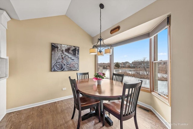 dining area with vaulted ceiling and light wood-type flooring