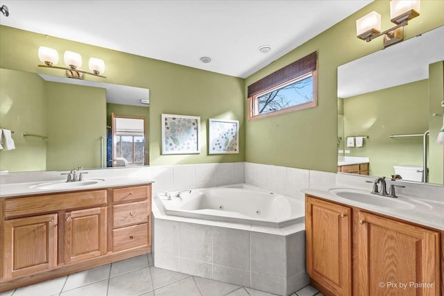 bathroom featuring tile patterned flooring, vanity, tiled bath, and toilet