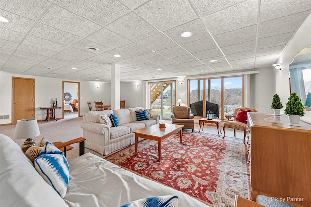 carpeted living room featuring a drop ceiling and a wealth of natural light