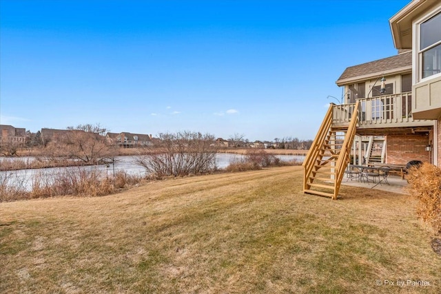 view of yard featuring a deck with water view and a patio