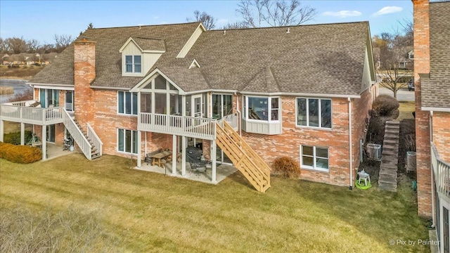 back of house with a wooden deck, a lawn, a sunroom, and a patio