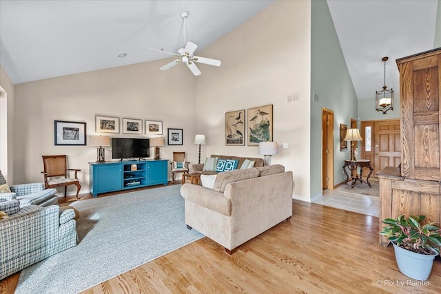 living room featuring ceiling fan with notable chandelier, high vaulted ceiling, and light hardwood / wood-style floors