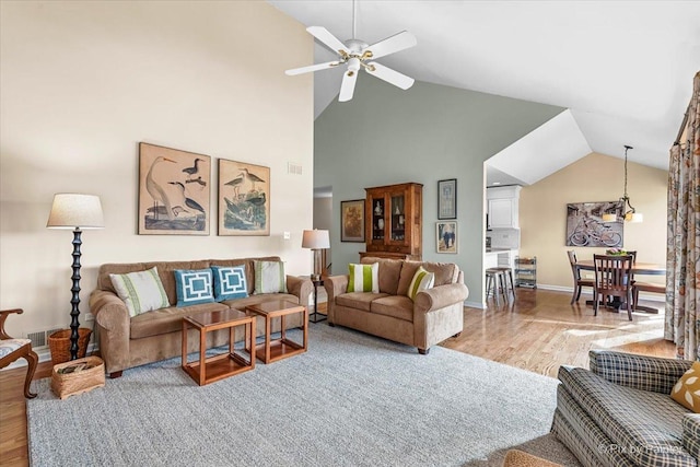 living room with high vaulted ceiling, ceiling fan, and light hardwood / wood-style flooring