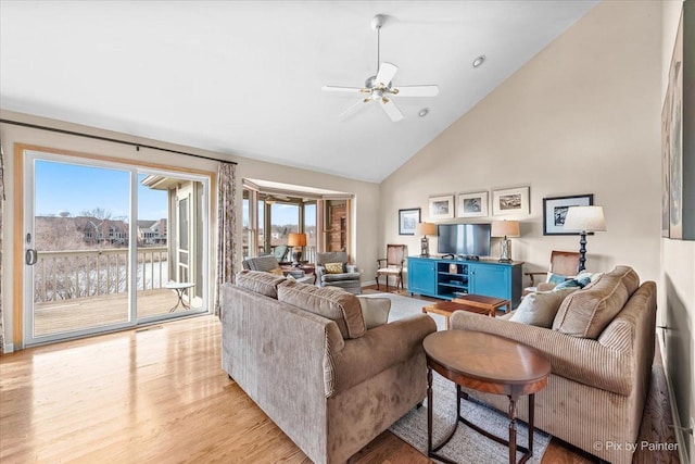 living room with light hardwood / wood-style flooring, high vaulted ceiling, and ceiling fan