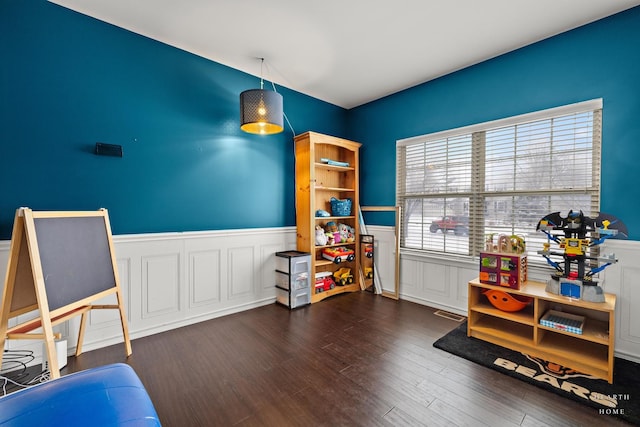 game room featuring dark wood-type flooring and a wainscoted wall