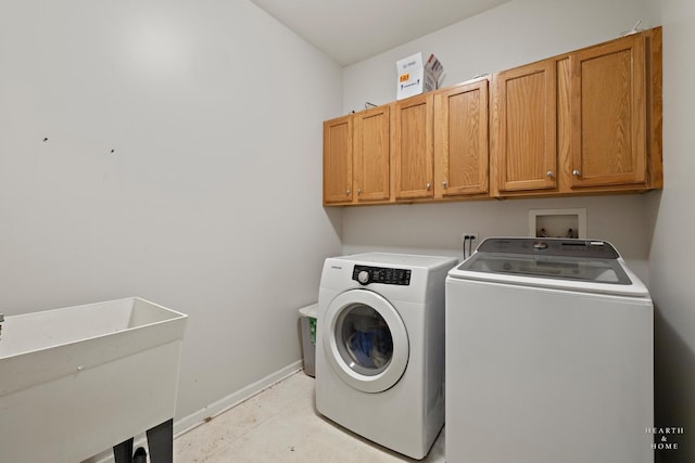 washroom with baseboards, cabinet space, a sink, and washing machine and clothes dryer