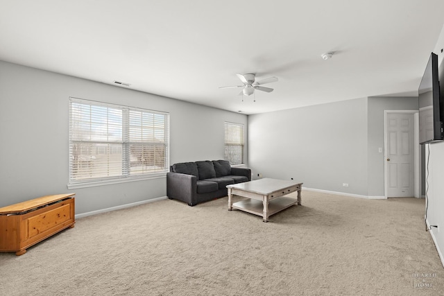 living area featuring baseboards, ceiling fan, visible vents, and light colored carpet