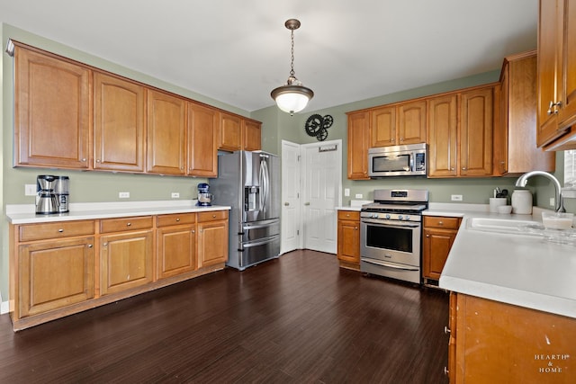 kitchen with dark wood-style floors, stainless steel appliances, hanging light fixtures, and light countertops