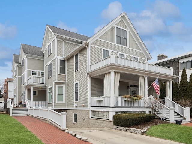 view of front of house featuring a balcony, covered porch, and a shingled roof