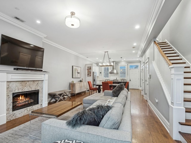 living room featuring baseboards, visible vents, stairway, wood finished floors, and crown molding