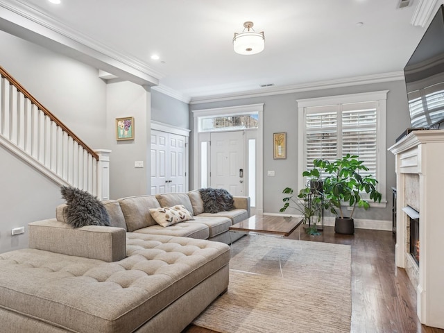 living room featuring dark wood-style flooring, crown molding, recessed lighting, a warm lit fireplace, and baseboards