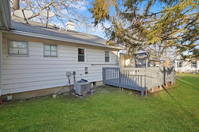 rear view of property with a yard, cooling unit, and a deck