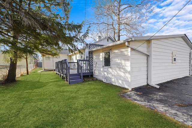 rear view of house featuring a wooden deck and a yard