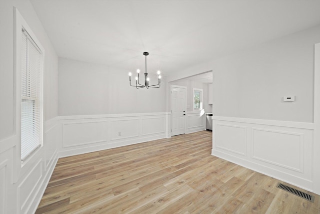 unfurnished dining area featuring a notable chandelier and light hardwood / wood-style flooring