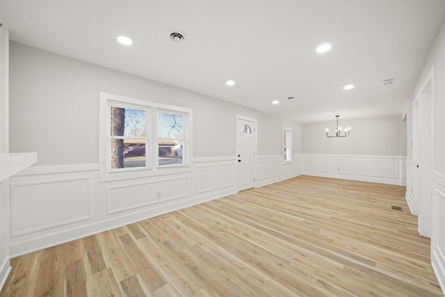 unfurnished room featuring an inviting chandelier and light hardwood / wood-style flooring