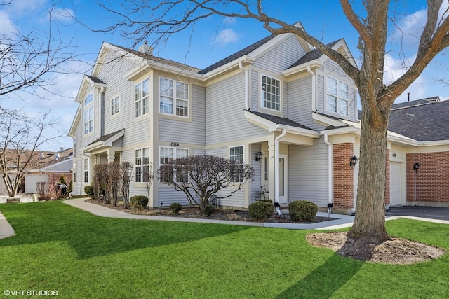 view of front of home featuring a garage, driveway, a front lawn, and brick siding