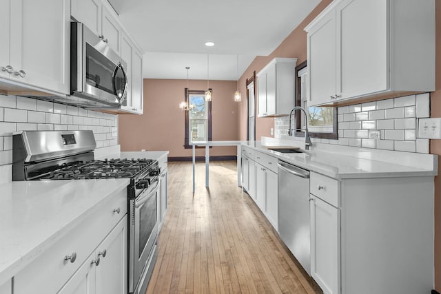 kitchen featuring pendant lighting, white cabinetry, appliances with stainless steel finishes, and sink