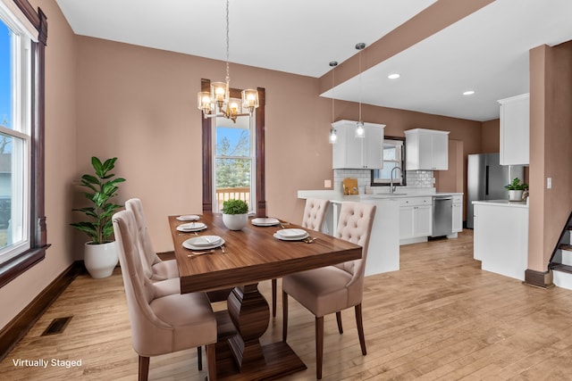 dining space featuring sink, an inviting chandelier, and light wood-type flooring