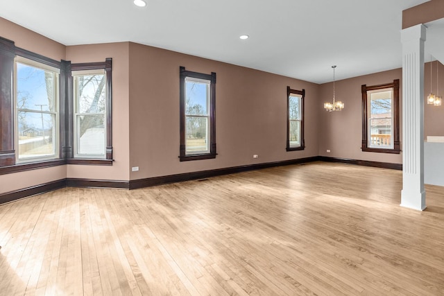 unfurnished room featuring light wood-type flooring and an inviting chandelier