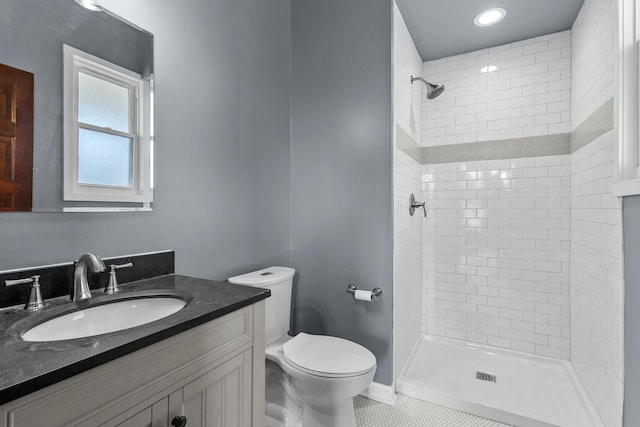 bathroom with tile patterned flooring, vanity, tiled shower, and toilet