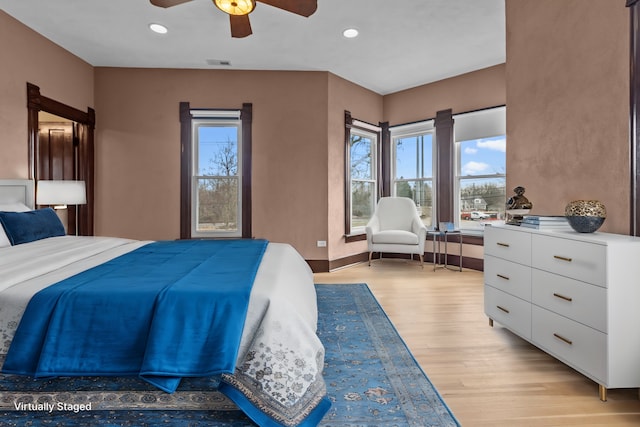 bedroom with multiple windows, ceiling fan, and light wood-type flooring