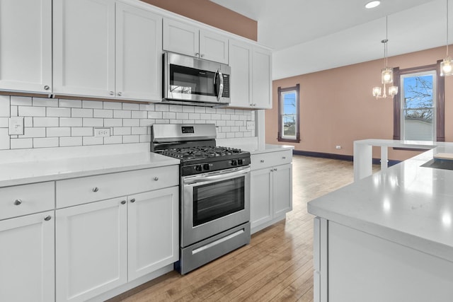 kitchen with stainless steel appliances, white cabinets, backsplash, and decorative light fixtures