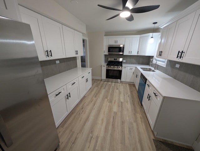 kitchen featuring stainless steel appliances, decorative light fixtures, sink, and white cabinets