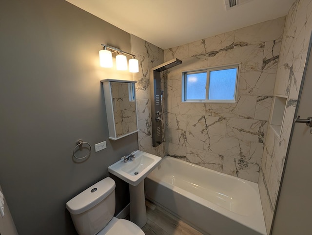 bathroom featuring tiled shower / bath and toilet