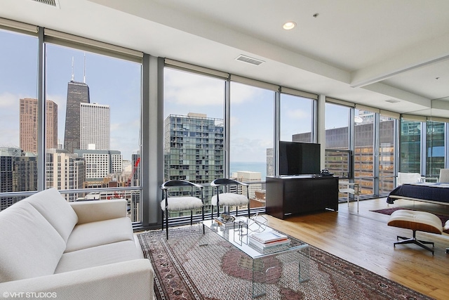 living room featuring beamed ceiling, a wall of windows, and wood-type flooring