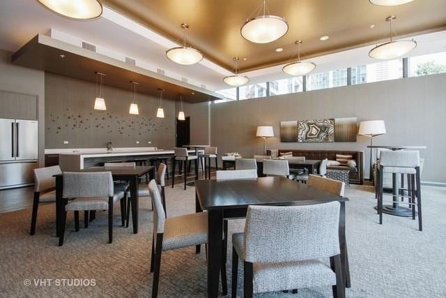 dining area with a tray ceiling, light carpet, and a high ceiling