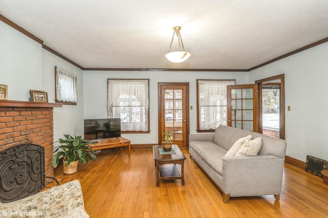 living room featuring ornamental molding, a brick fireplace, and light hardwood / wood-style flooring