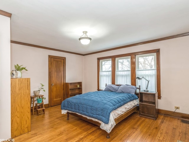 bedroom with ornamental molding and light hardwood / wood-style flooring