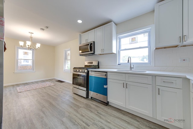 7345 S Washtenaw Ave, Chicago, IL 60629 - kitchen featuring tasteful backsplash, light wood-type flooring, stainless steel appliances, sink, and white cabinetry