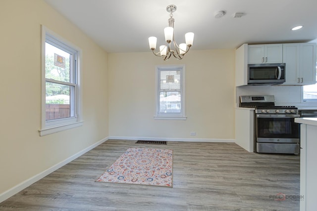 7345 S Washtenaw Ave, Chicago, IL 60629 - kitchen featuring white cabinets, hanging light fixtures, appliances with stainless steel finishes, and plenty of natural light