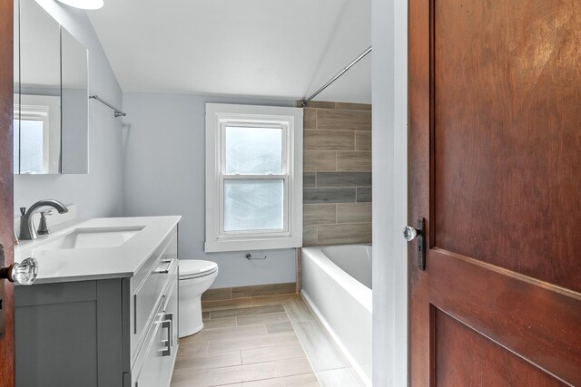 full bathroom featuring vanity, toilet, tiled shower / bath combo, and vaulted ceiling