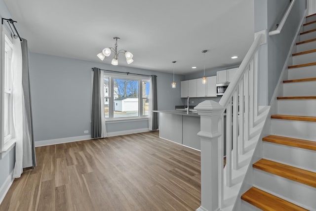 kitchen featuring sink, a breakfast bar area, white cabinetry, decorative light fixtures, and light hardwood / wood-style flooring