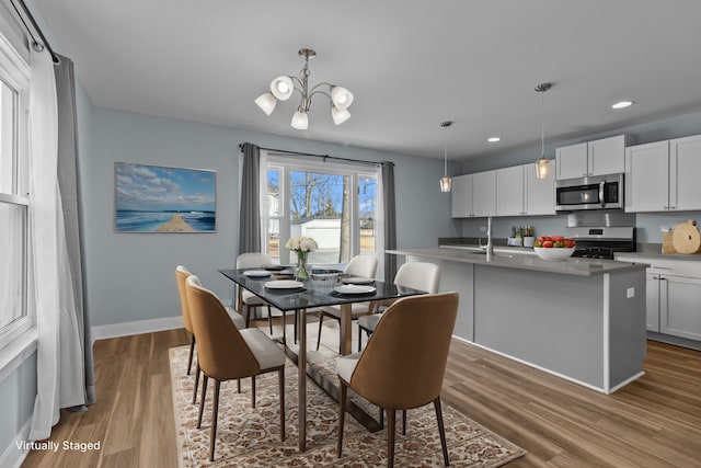 dining room with sink, hardwood / wood-style floors, and a notable chandelier