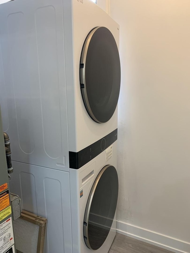 clothes washing area featuring dark hardwood / wood-style flooring and stacked washer and clothes dryer