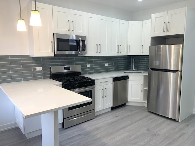 kitchen featuring sink, white cabinets, hanging light fixtures, light stone counters, and stainless steel appliances