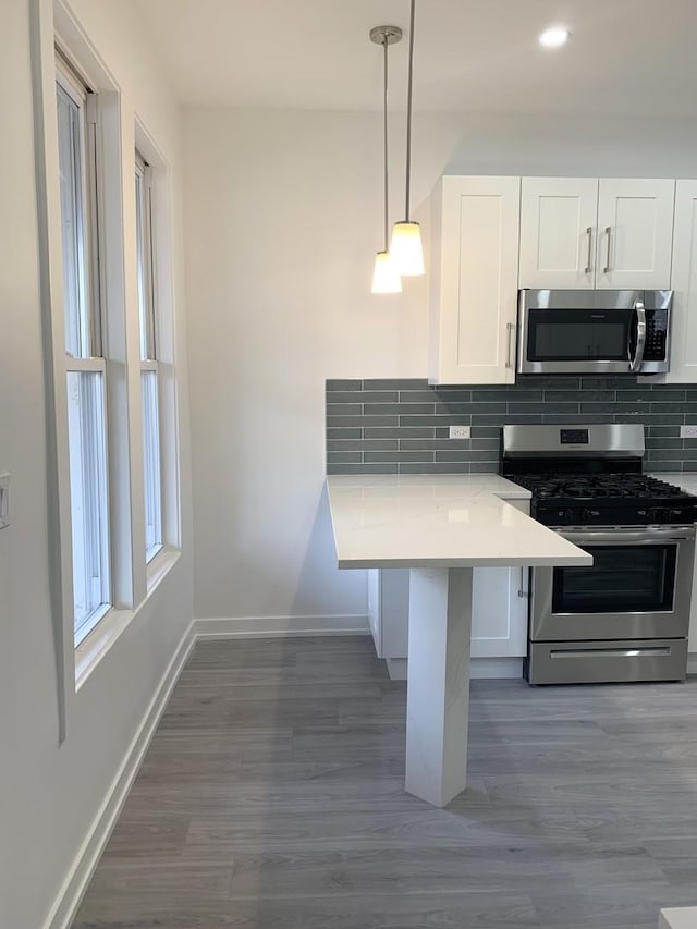 kitchen featuring white cabinetry, pendant lighting, stainless steel appliances, and kitchen peninsula