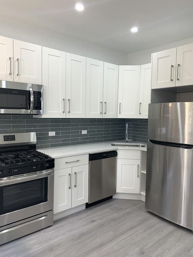 kitchen with stainless steel appliances, decorative backsplash, and white cabinets