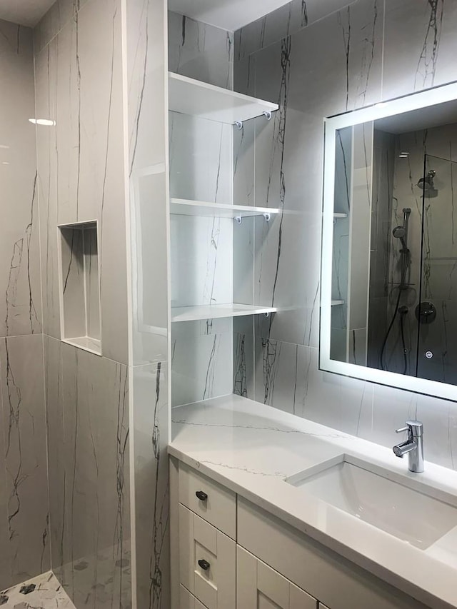 bathroom with a tile shower and vanity