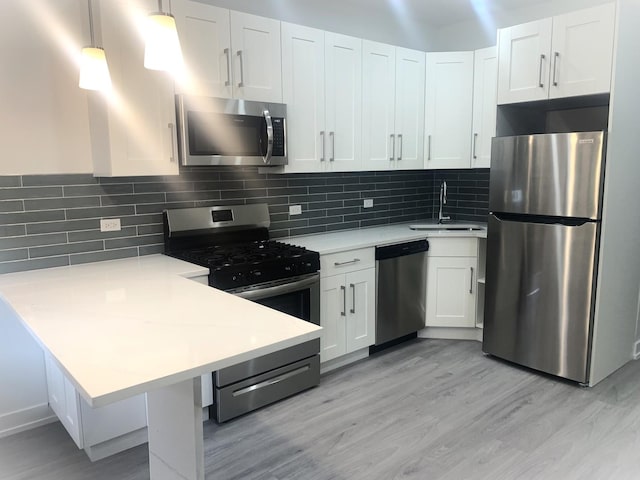 kitchen with appliances with stainless steel finishes, decorative light fixtures, sink, white cabinets, and decorative backsplash