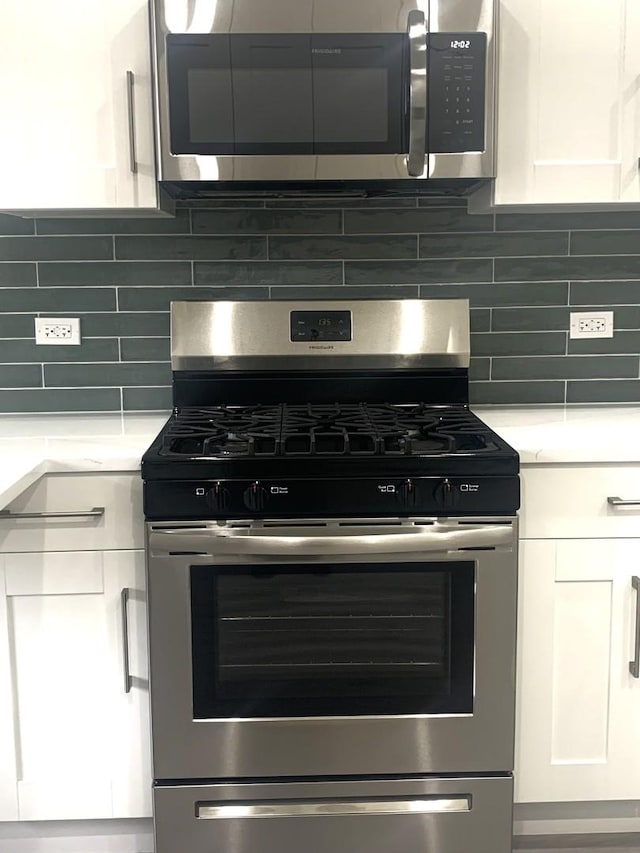 interior details with stainless steel appliances, white cabinets, and backsplash