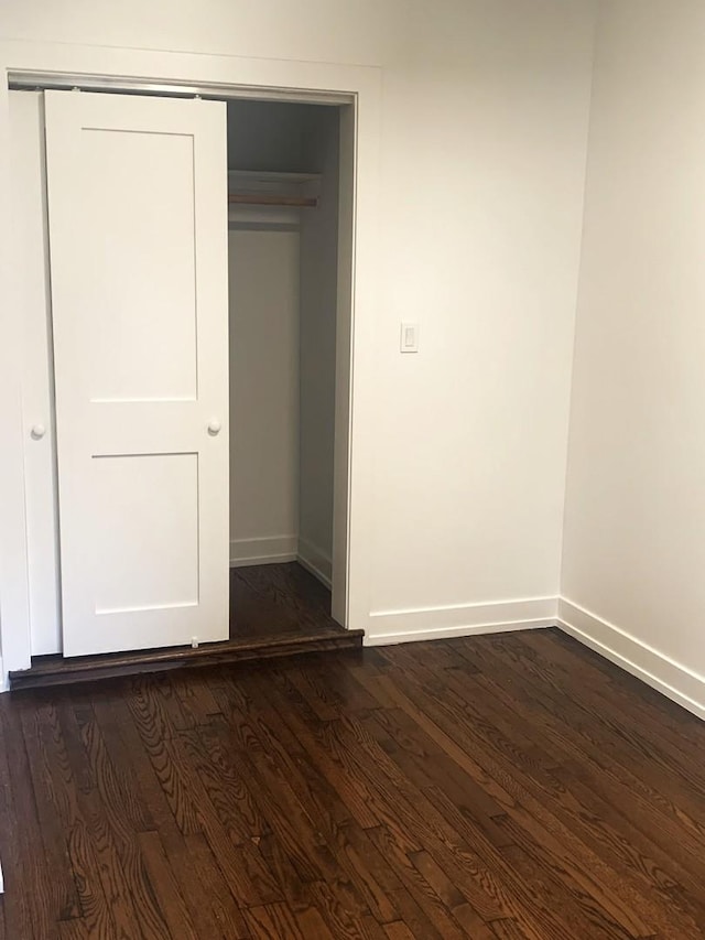 unfurnished bedroom with dark hardwood / wood-style floors and a closet