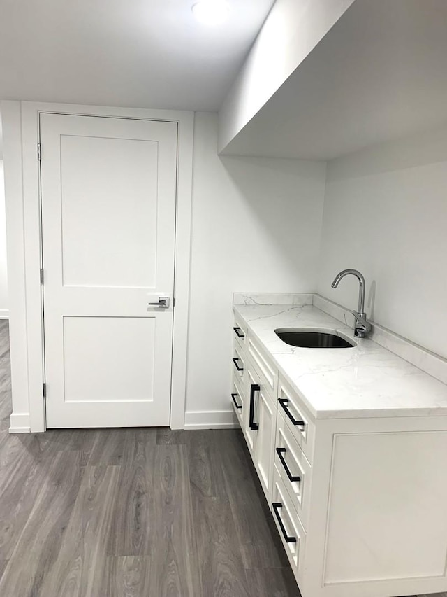 interior space with light stone counters, white cabinetry, dark wood-type flooring, and sink