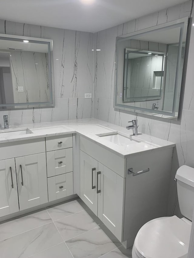 bathroom featuring vanity, tile walls, and toilet