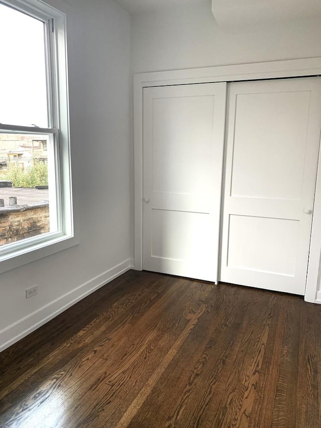 unfurnished bedroom with dark hardwood / wood-style flooring and a closet